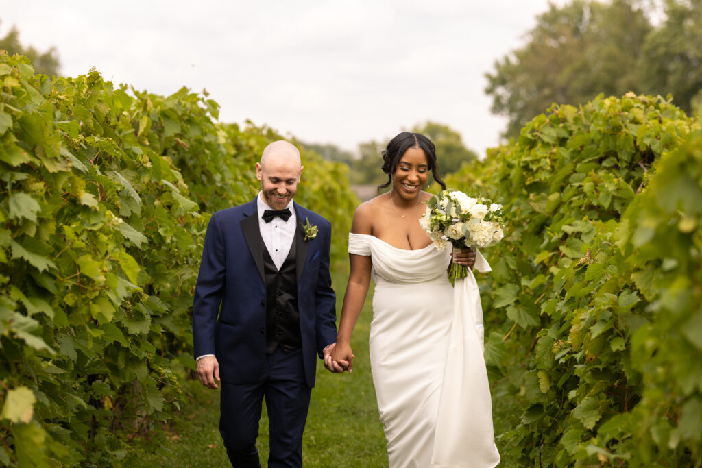 Groom and bride happily walk down the aisles of a vineyard at Gervasi Vineyard located in Canton Ohio. Photo taken by Cleveland Wedding Photographer Aaron Aldhizer