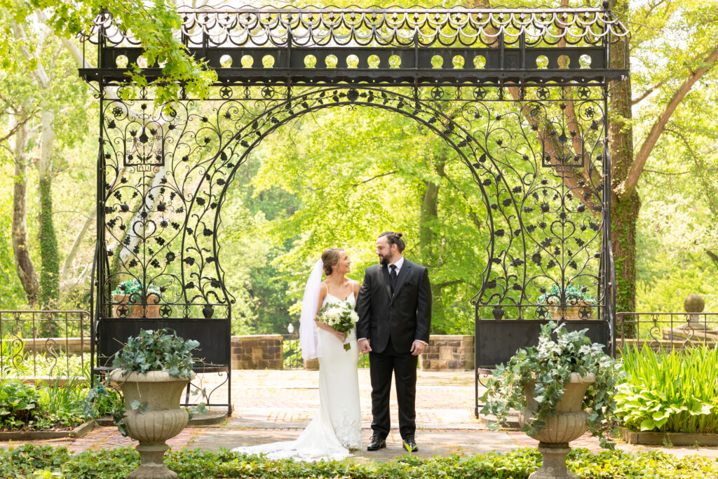 bride and groom in a white dress and black tux, fondly look at one another  in Cleveland Cultural Gardens on their wedding day. Photo taken by Cleveland wedding photographer Aaron Aldhizer