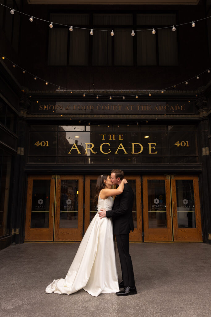 husband and wife kiss one another outside of the entrance of The Arcade in downtown Cleveland Ohio. Photo taken by Cleveland wedding photographer Aaron Aldhizer